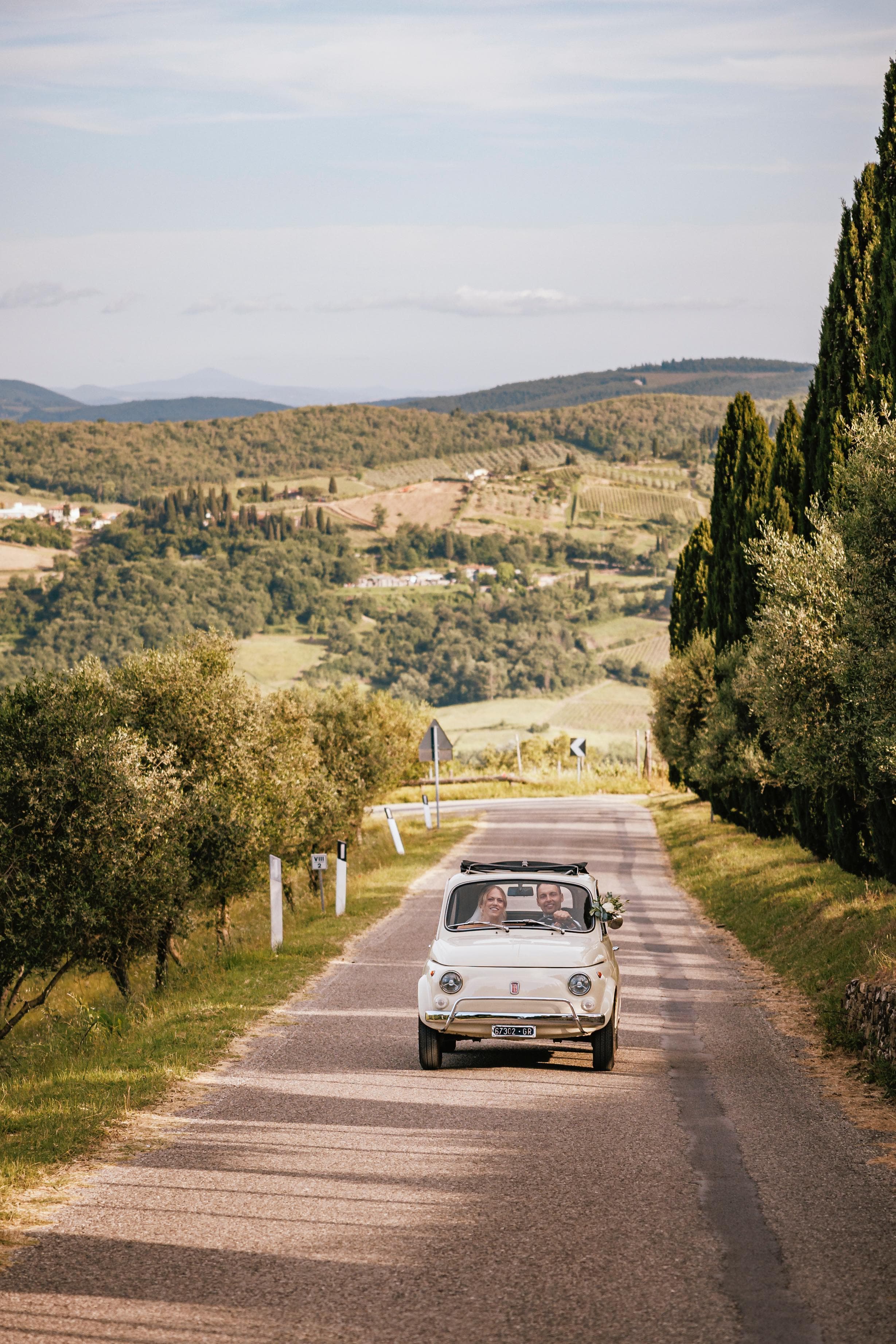 Fiat 500 vintage su strada toscana con cipressi